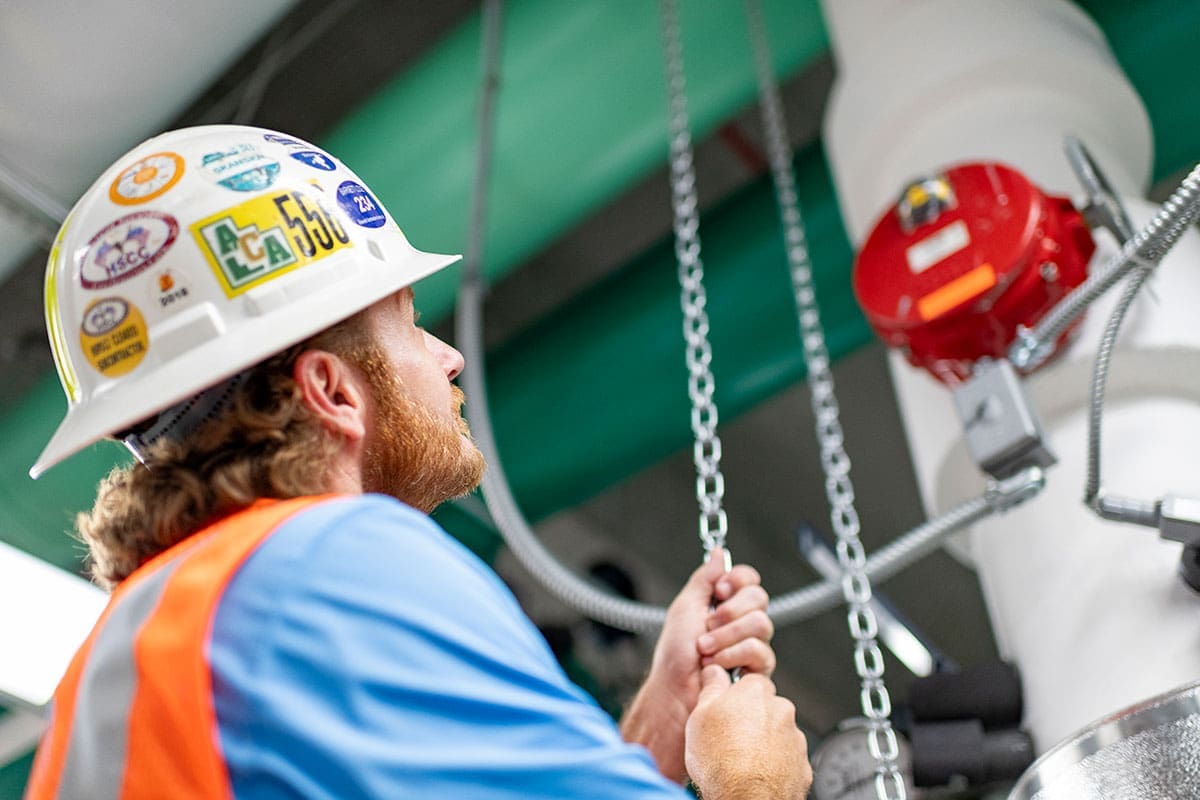 construction-worker-hard-hat-safety-vest-operating-chain-industrial-equipment-sita. Construction worker in hard hat and safety vest operating chain mechanism on industrial equipment