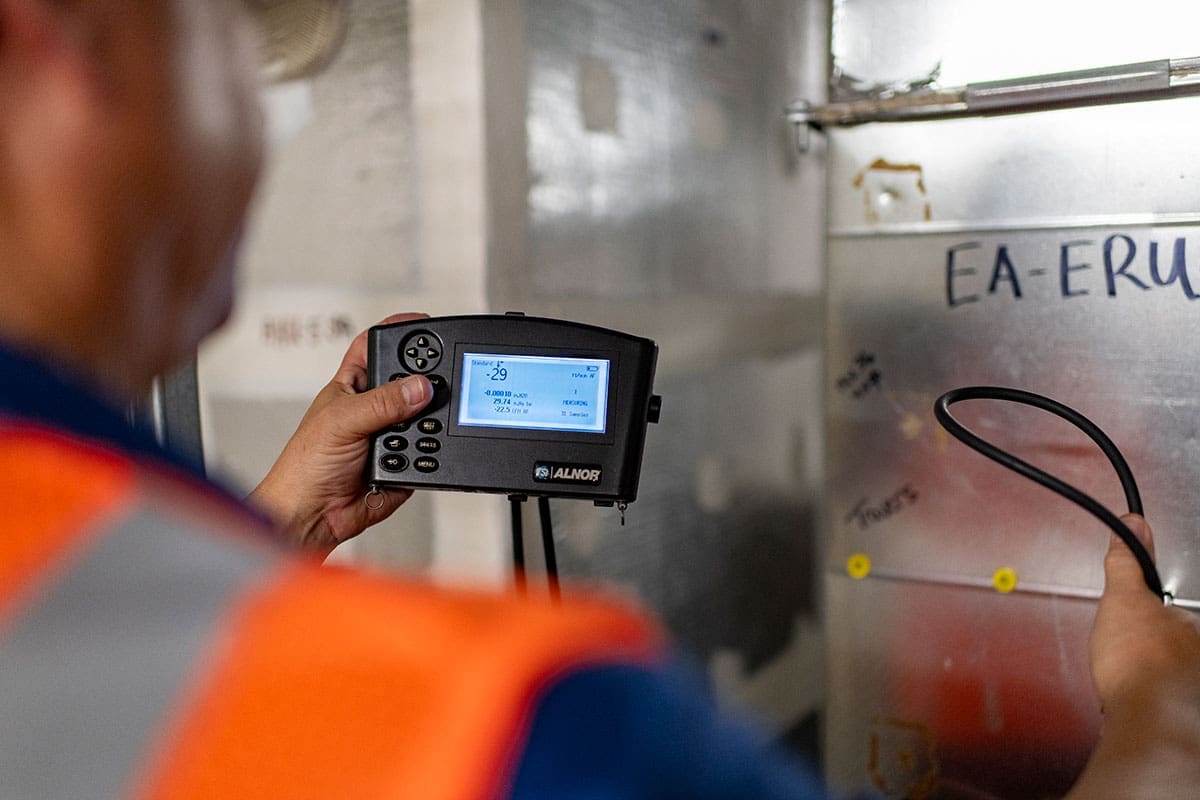 technician-alnor-pressure-measurement-device-ductwork-testing-sita. Technician holding an Alnor pressure measurement device while testing sheet metal ductwork