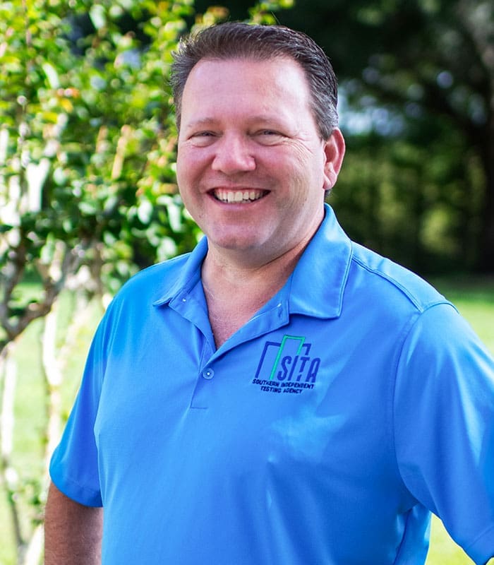 smiling-professional-in-sita-shirt-outdoors-sita. Keith W. Bunner ,the Sr. Project Analyst from SITA, outdoors posing and smiling in his blue SITA golfer