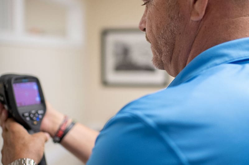 technician-flir-thermal-imaging-camera-interior-building-scan-sita. Technician holding a FLIR thermal imaging camera during a building inspection