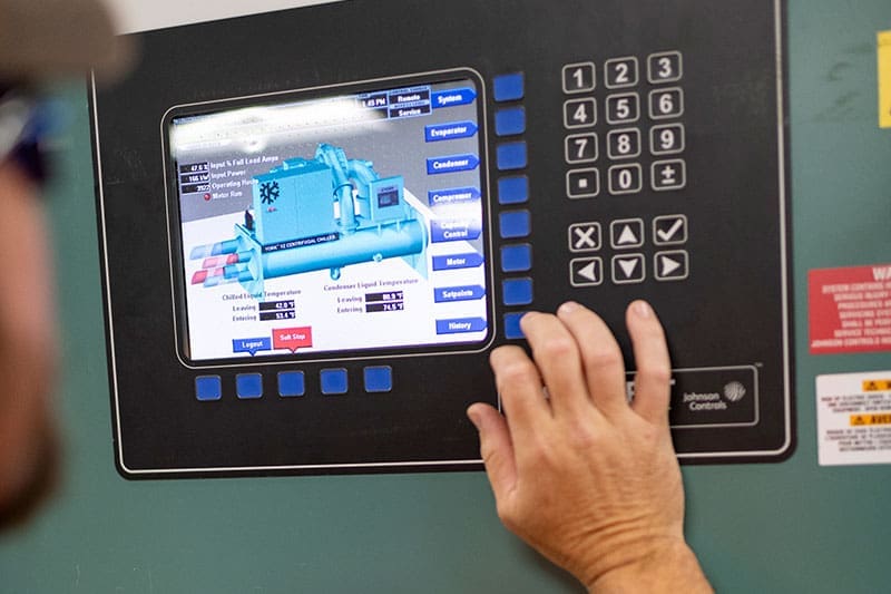 johnson-controls-centrifugal-chiller-control-panel-touchscreen-operation-sita. Technician operating a Johnson Controls centrifugal chiller control panel touchscreen