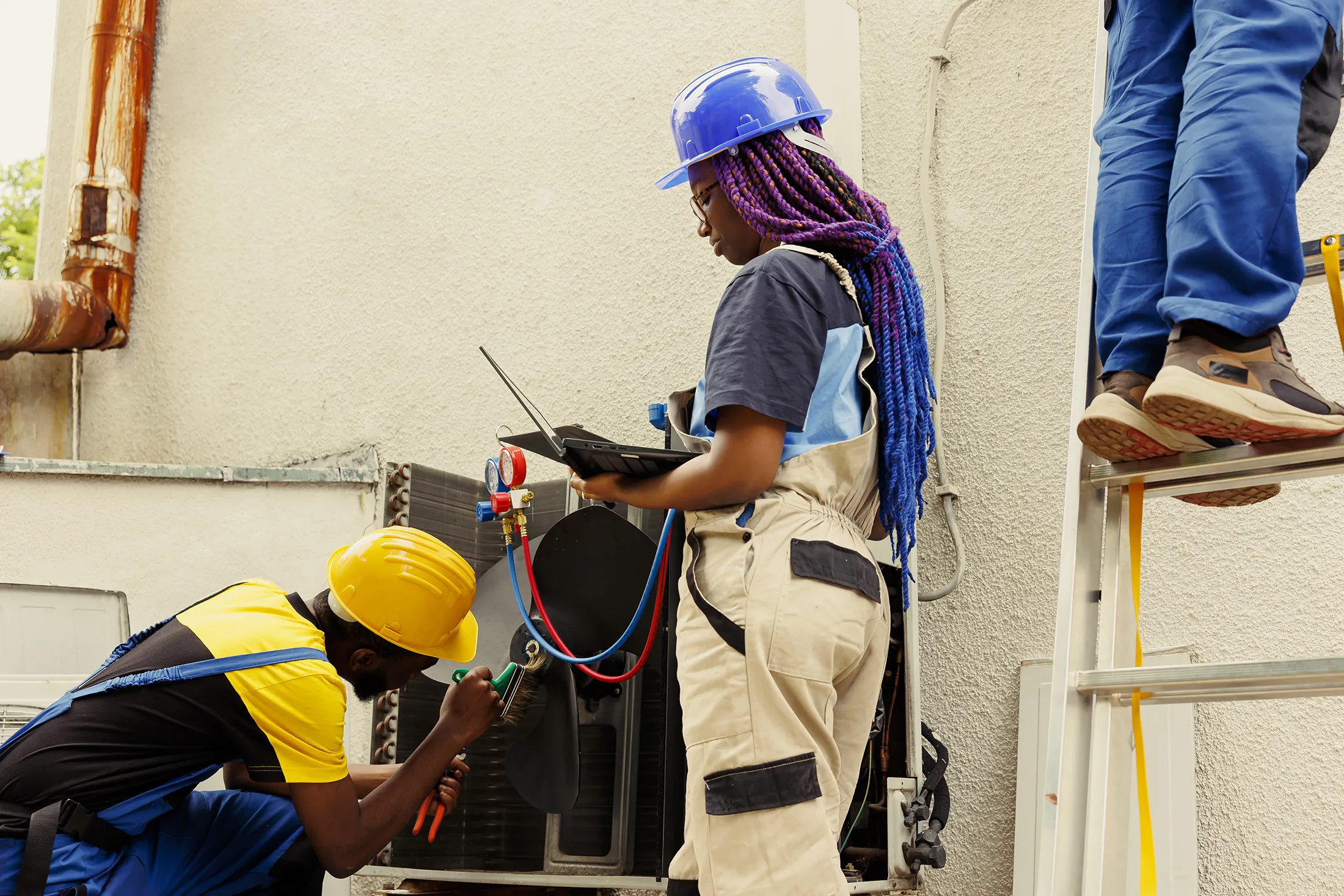 hvac-technicians-servicing-outdoor-condenser-unit-sita. HVAC technicians servicing an outdoor condenser unit while monitoring system diagnostics and maintenance performance.