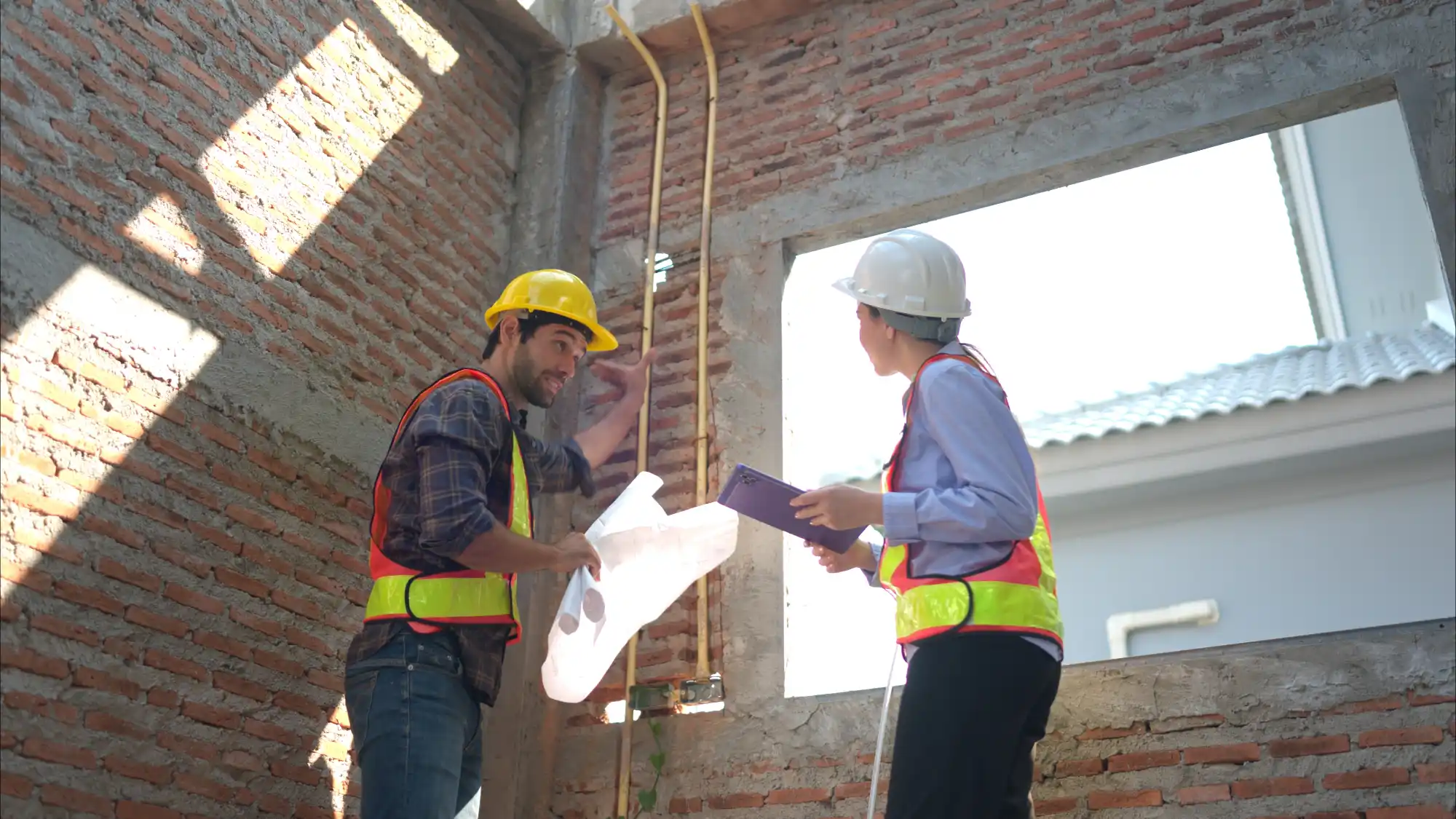 construction-workers-reviewing-building-specifications-sita. Two construction workers in hard hats review building plans and specifications at an active commercial construction site
