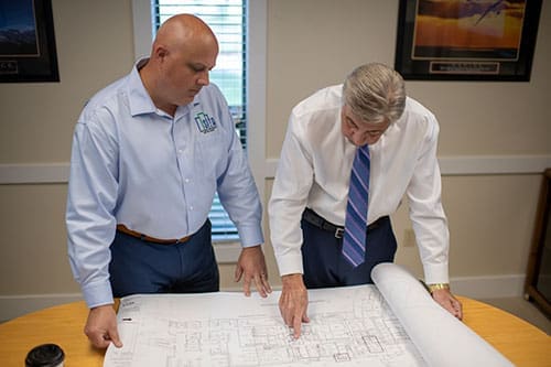 professionals-discussing-building-plans-over-table-sita. Two professionals discussing building plans over a table.