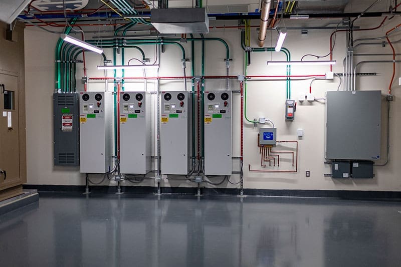industrial-electrical-control-panels-in-utility-room-sita. Row of industrial electrical control panels installed along a wall in a utility room.
