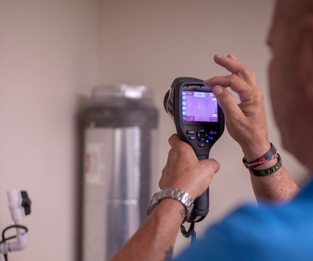 technician-flir-thermal-imaging-camera-building-equipment-inspection-sita. Technician using a FLIR thermal imaging camera to inspect building equipment