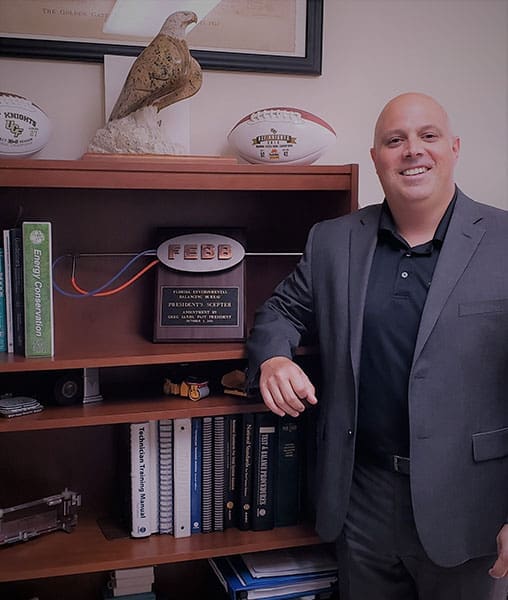 brian-kaupp-professional-headshot-office-awards-sita. Professional portrait of Brian Kaupp standing in his office beside awards, certifications, and industry accomplishments.